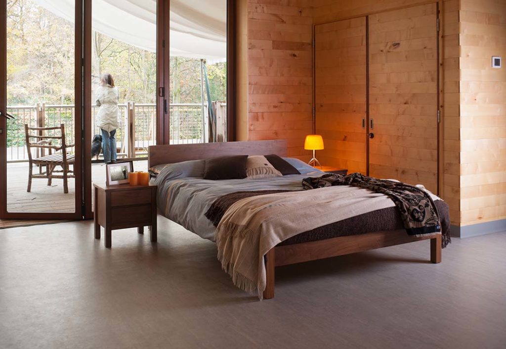 Country bedroom featuring our Sahara contemporary wooden bed in solid walnut with walnut Shaker bedside chest