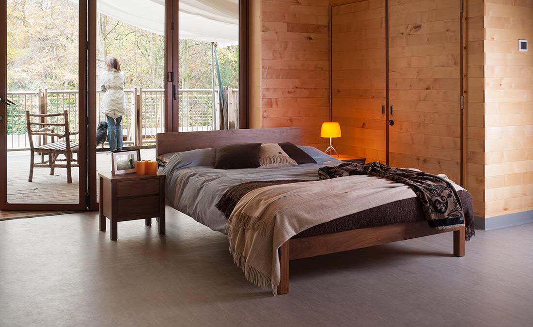 Country bedroom featuring our Sahara contemporary wooden bed in solid walnut with walnut Shaker bedside chest