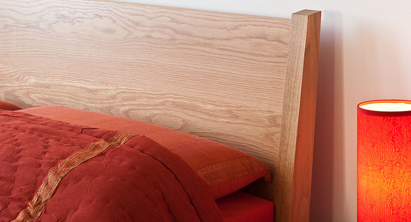 Close up of the sloping headboard of our Zanskar solid wooden bed in Oak