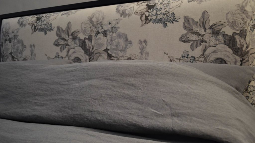 grey linen bedding on black shetland bed showing floral printed padded headboard