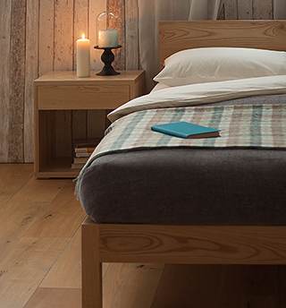 A cosy rustic bedroom featuring our solid wood malabar bed in Ash with Ash bedside Cube table