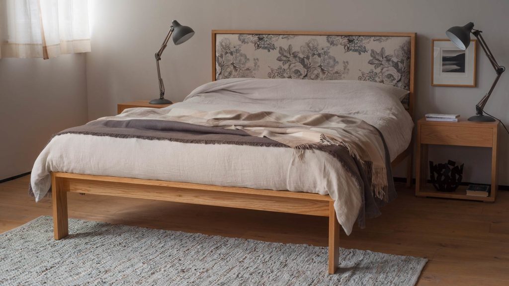 Shetland wooden bed with upholstered headboard shown in oak with Oak Cube tables as bedsides