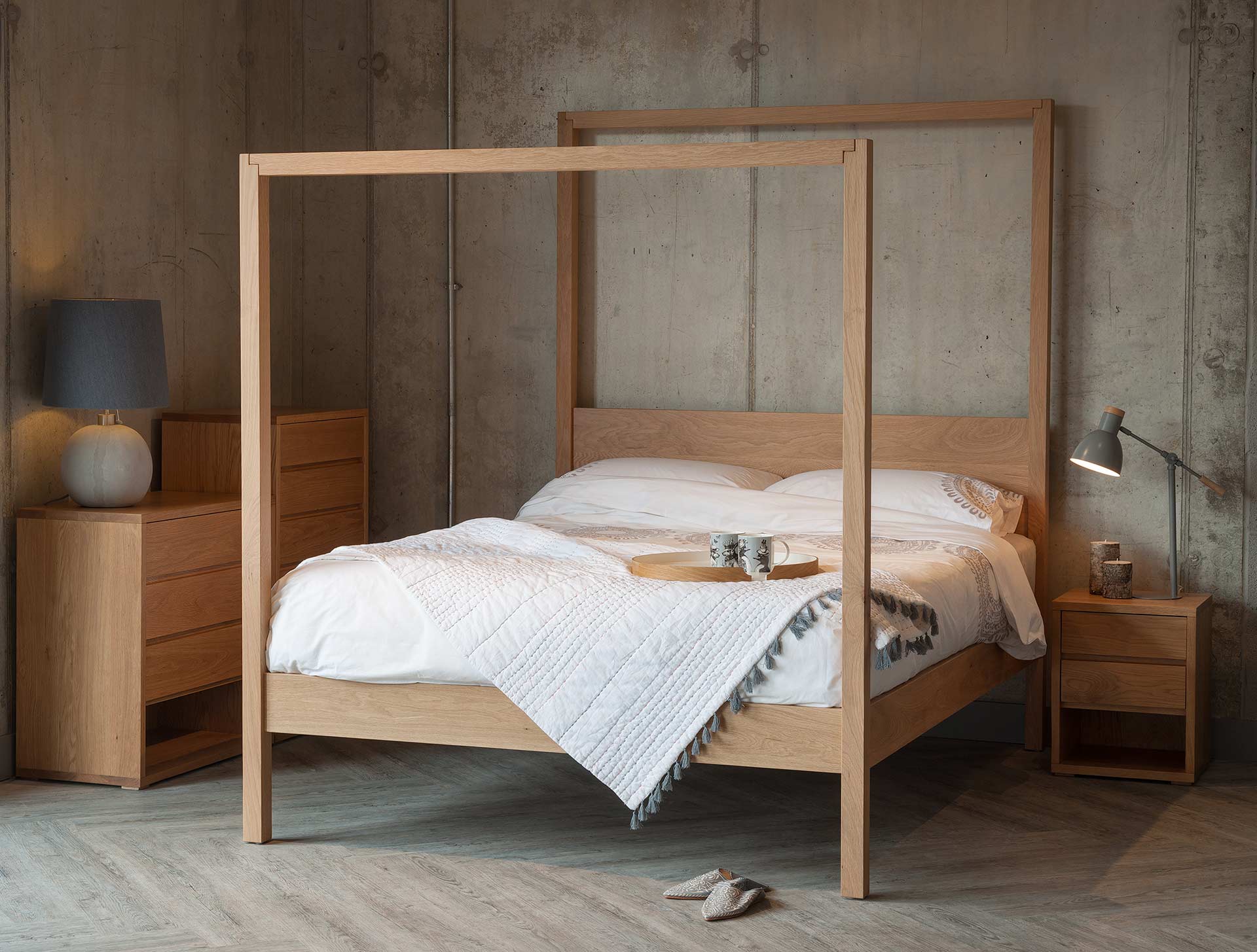 Oasis modern four poster bed hand made from solid wood shown with Oak Cube bedroom storage furniture.