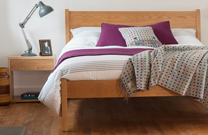 Classic Zanskar a taller solid wooden bed in Oak, made in UK, shown with Oak Cube bedside table.