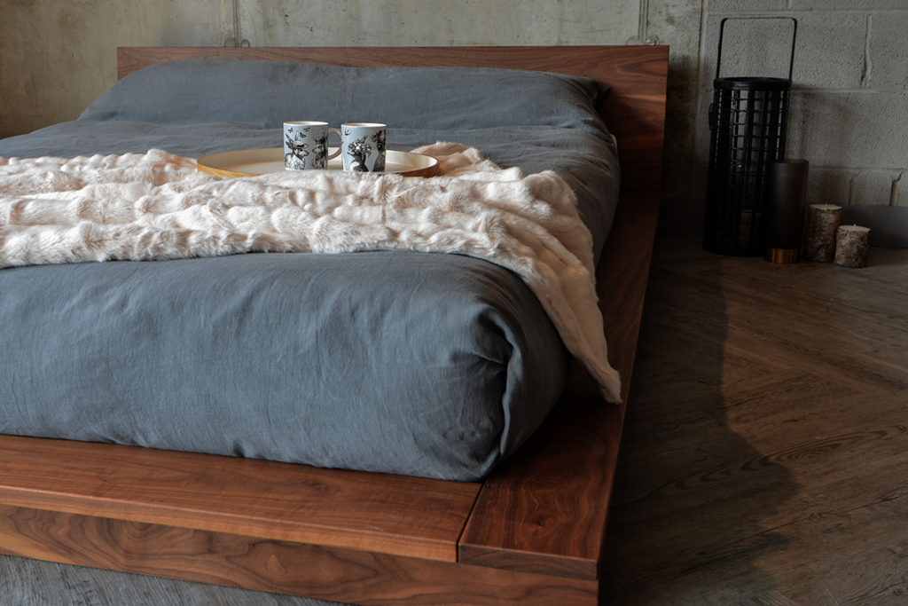 grey linen bedding and fluffy throw on low platform Oregon wooden bed