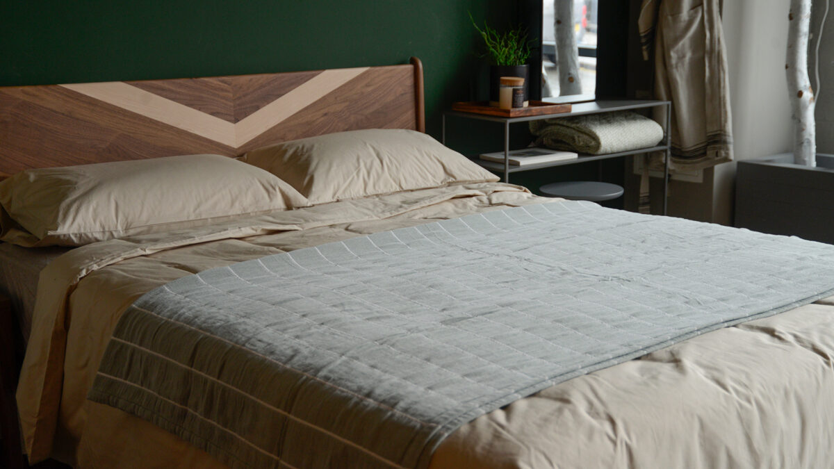 Jade green striped cotton throw shown on a kingsize bed