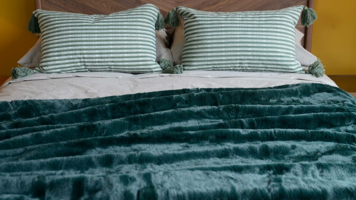 soft faux fur throw in forest green shown on a bed