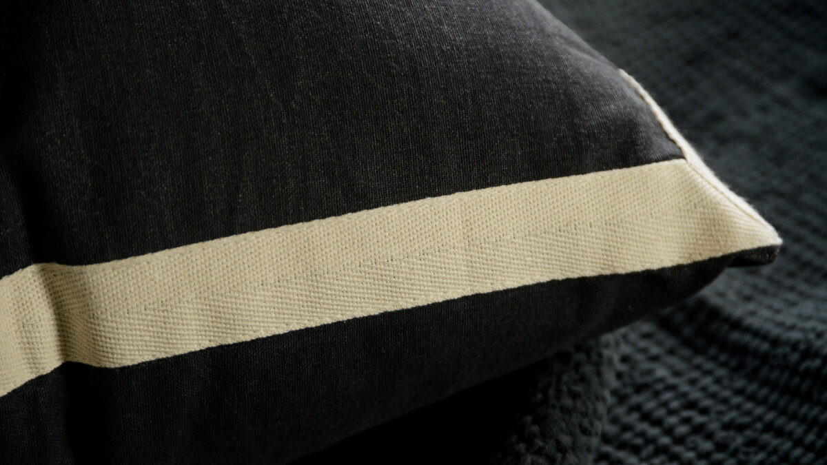 black cotton cushions with ivory coloured edges shown close up