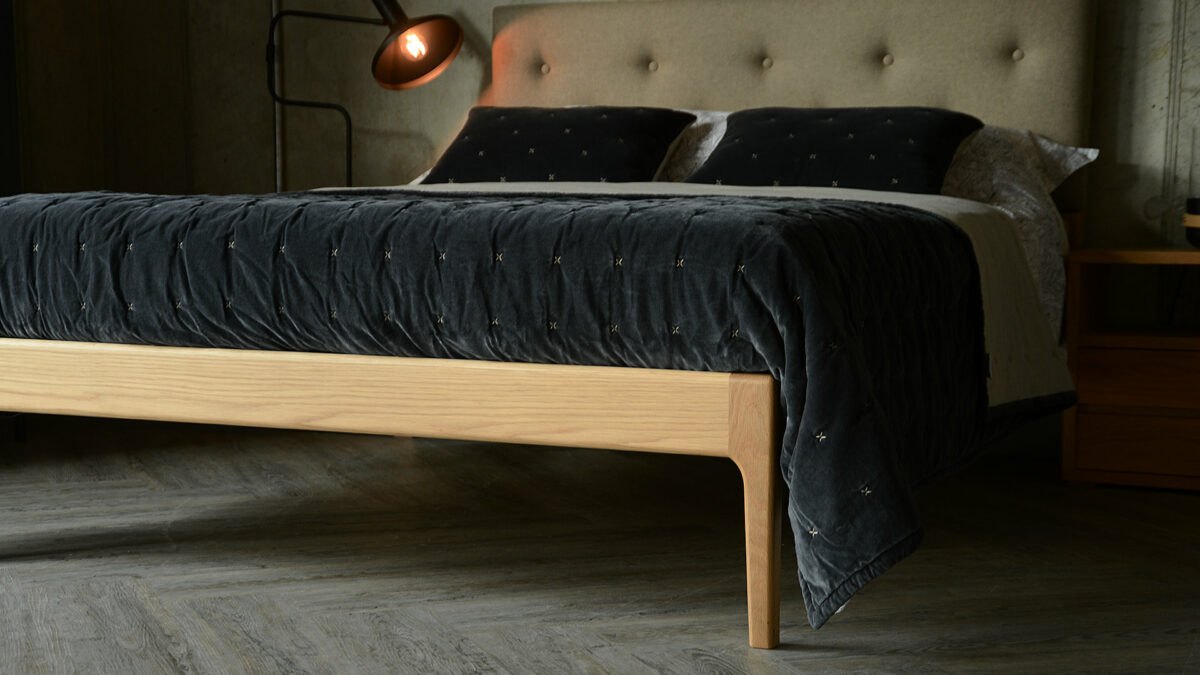 Bloomsbury a solid oak bed with curved legs and an upholstered and buttoned headboard