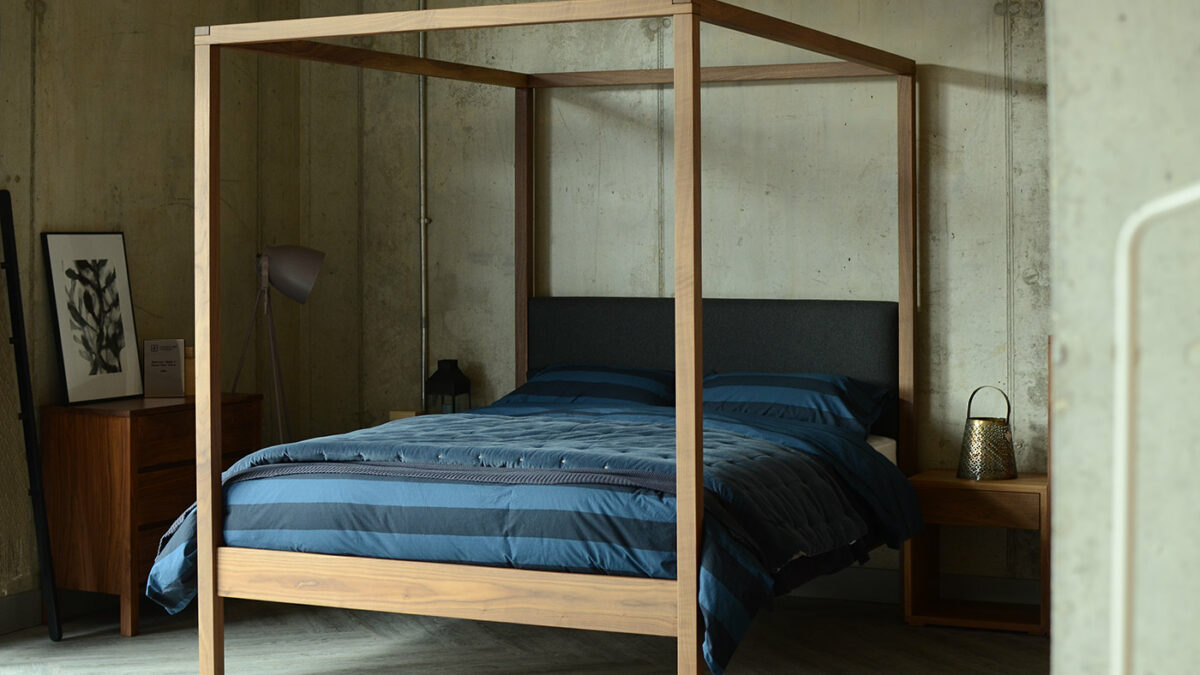 Industrial look bedroom featuring the Highland 4 poster bed in walnut with grey wool padded headboard