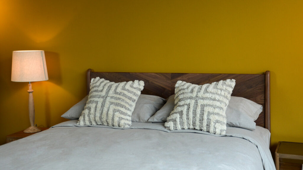 Tufted and textured cotton cushions in a brown and cream design shown on a bed