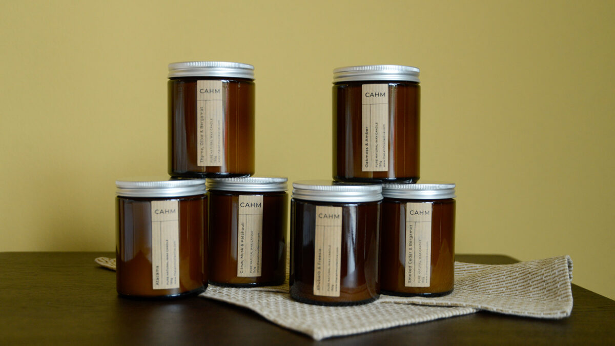 6 cahm candles stacked on a cloth on top of a walnut counter.