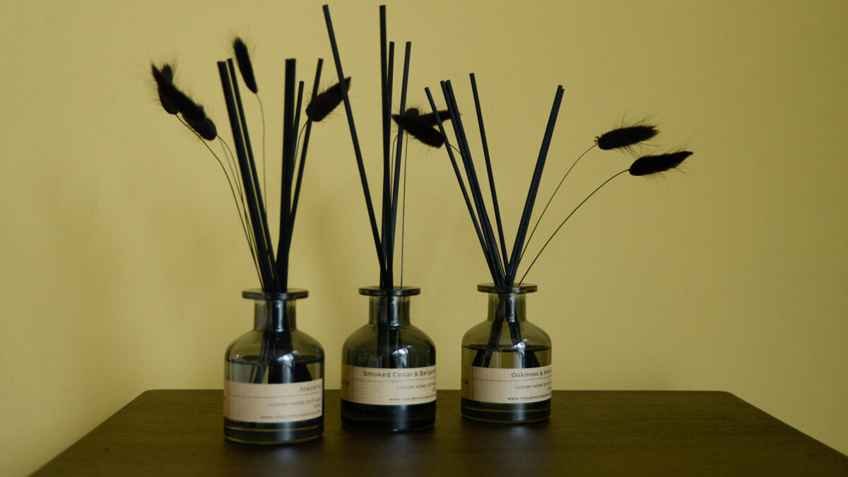 3 diffusers with luxury reeds sat on dark tabletop.