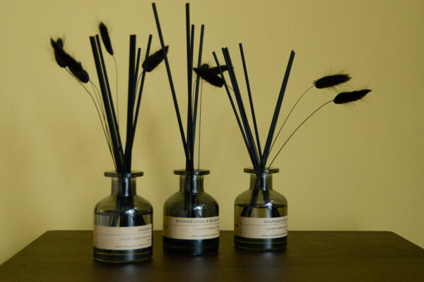 3 diffusers with luxury reeds sat on dark tabletop.