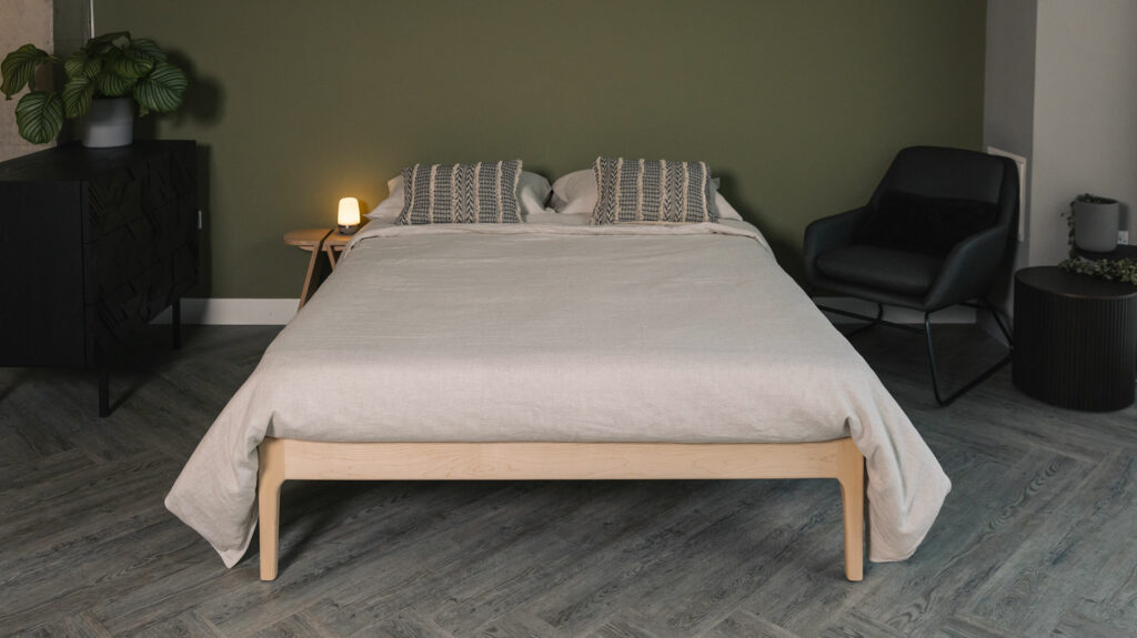 Maple wood Camden bed frame without a headboard and shown with taupe linen bedding