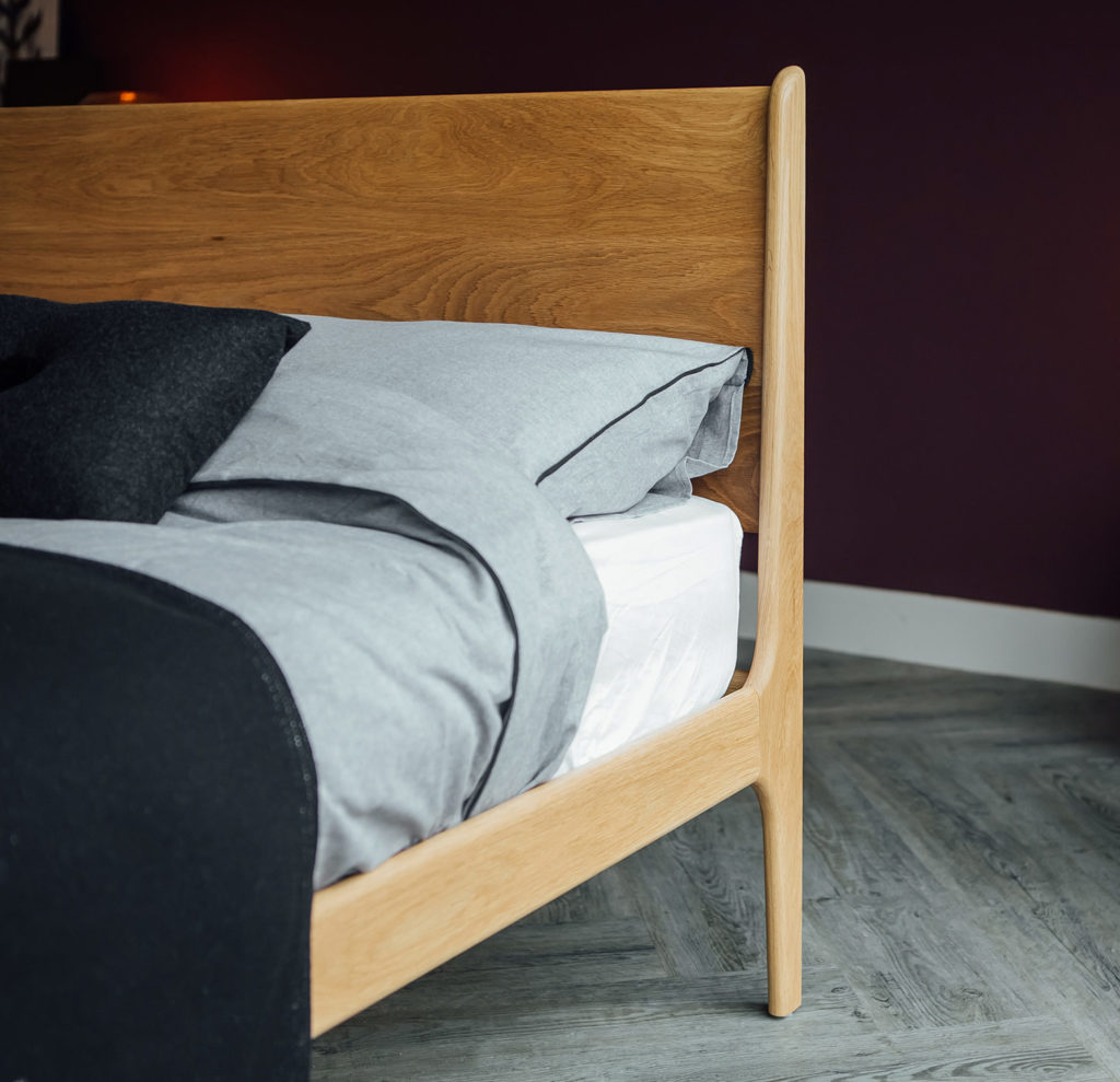 A close-up shot of the Camden Bed solid wood Headboard and curving leg