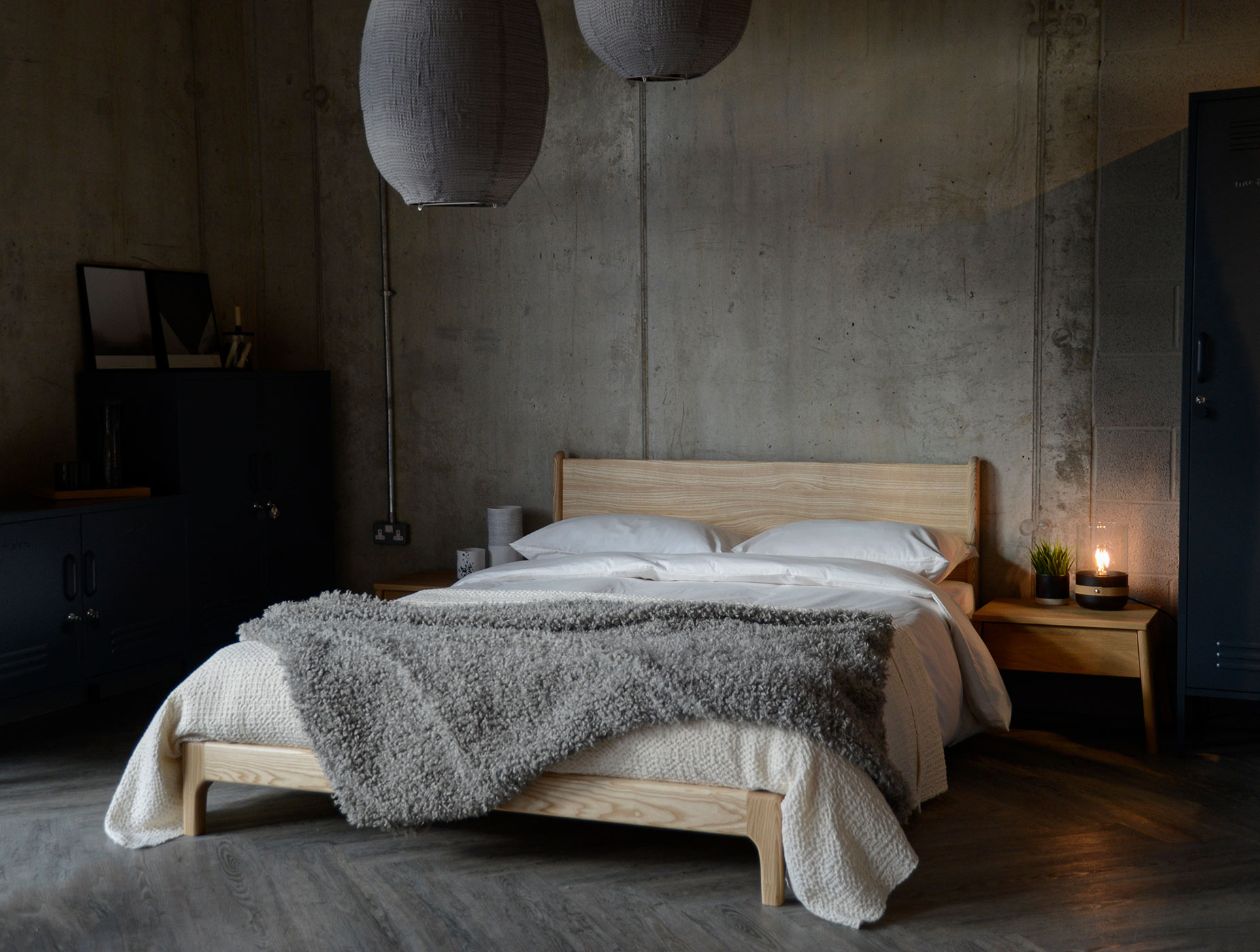 A low hand made Arts and Crafts style wooden bed, in an industrial bedroom setting, the Carnaby in solid ash