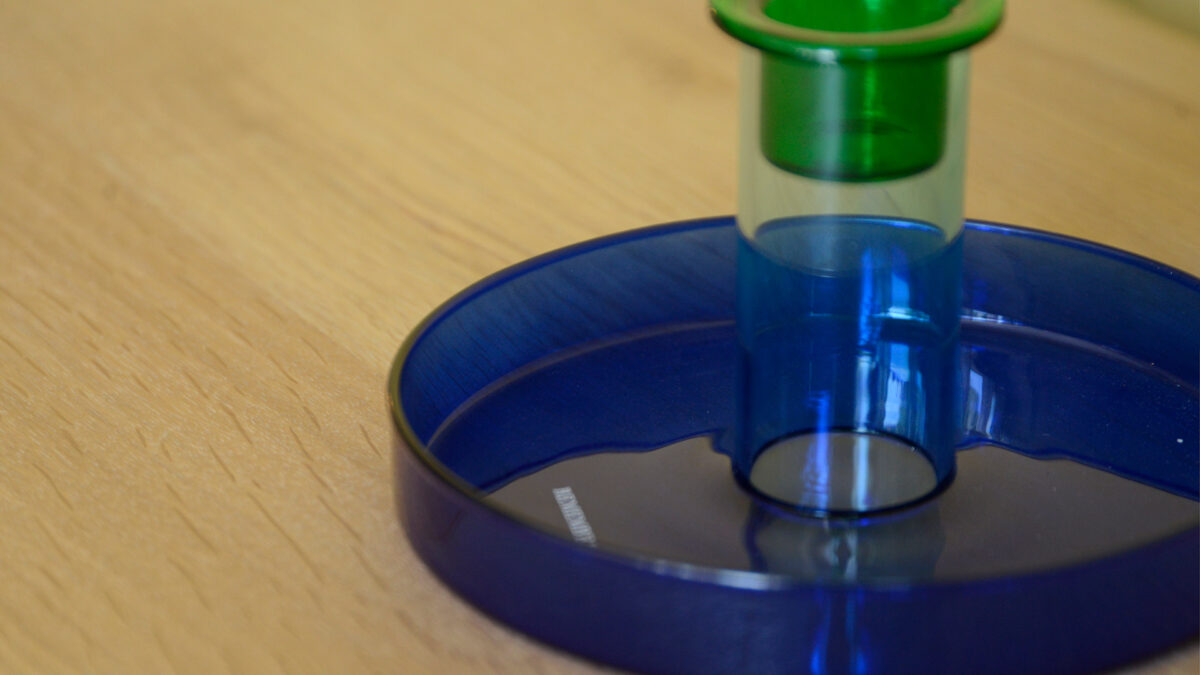 Closeup image of a glass candleholder in a bright, rich blue colour with a green glass insert just visible to the top of the image, for holding candles.