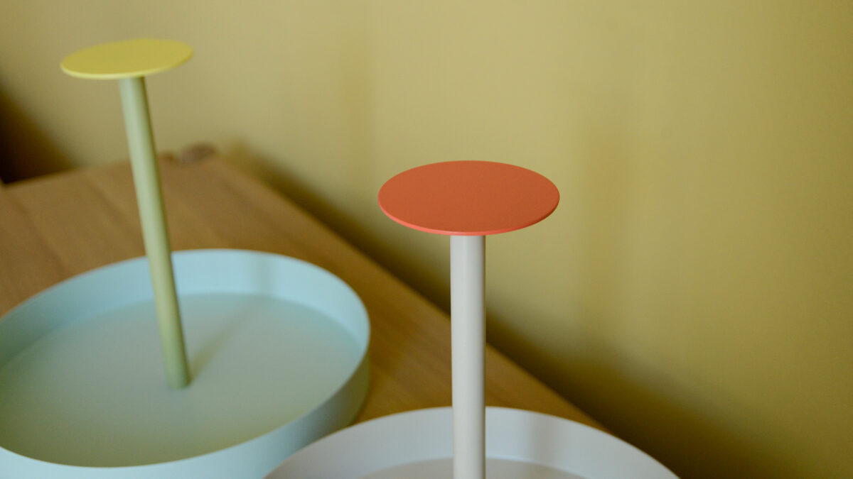 Close up of coral handle at the top of round metal tray. Second tray in the background.