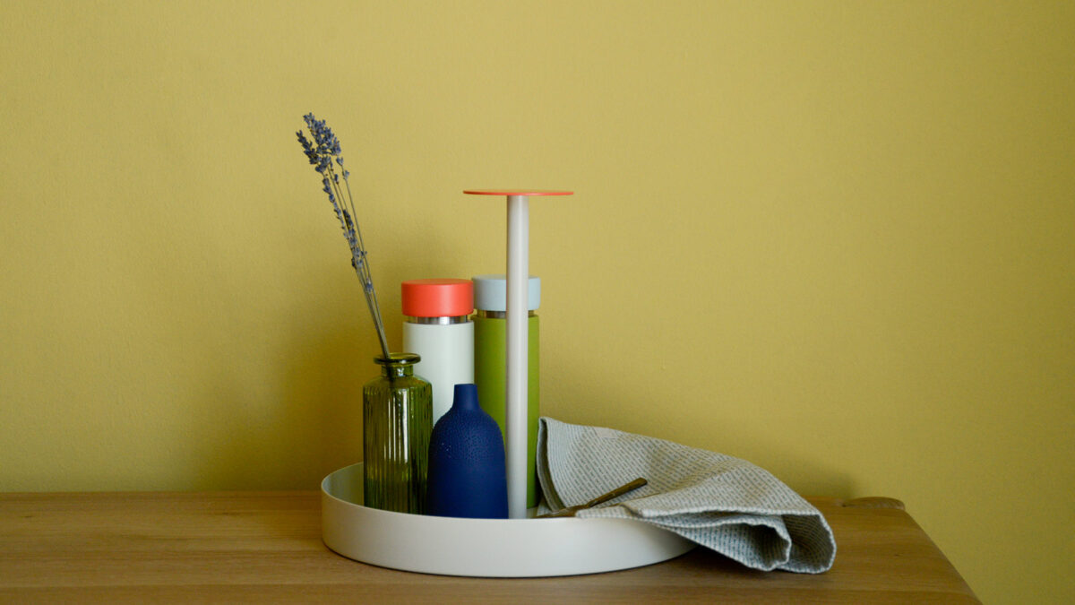 Grey round metal tray with coral handle and kitchen accessories.