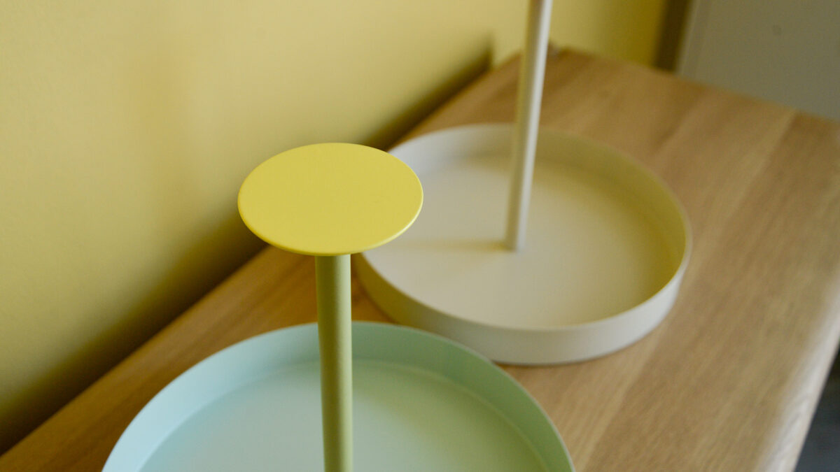 close up of round handle on top of round metal trays - bright yellow.