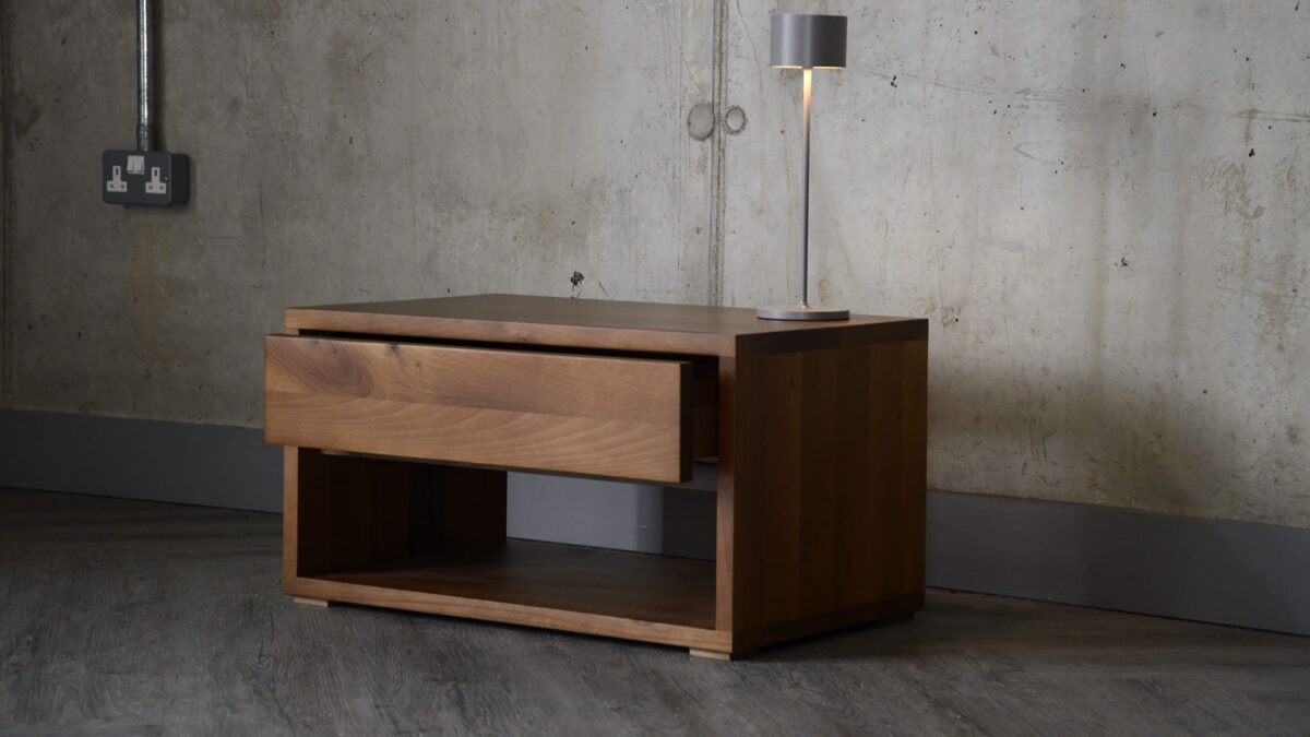 Image showing the Black Lotus one drawer bedside in walnut with a rechargeable lamp sat atop it.