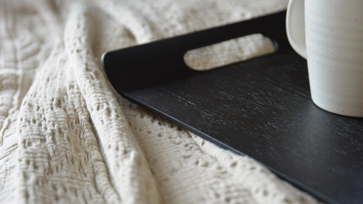 close up of the corner of a curved black tray with a hand hole.
