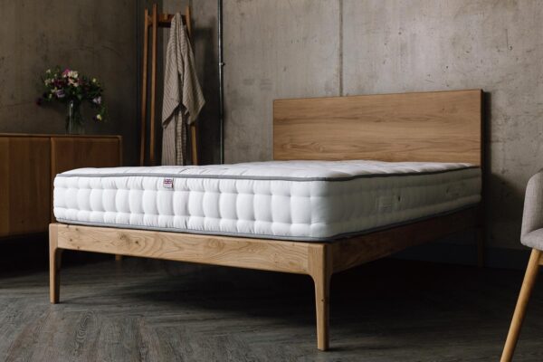 A low angled shot of the English oak Chiswick, which has a bare mattress on top of it.