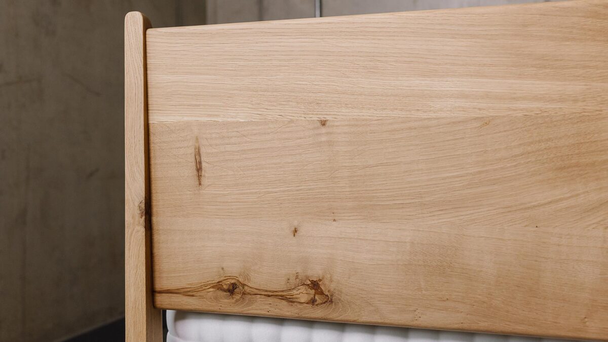 close up of the back of the headboard on a solid English Oak Camden bed. Visible knots in grain.