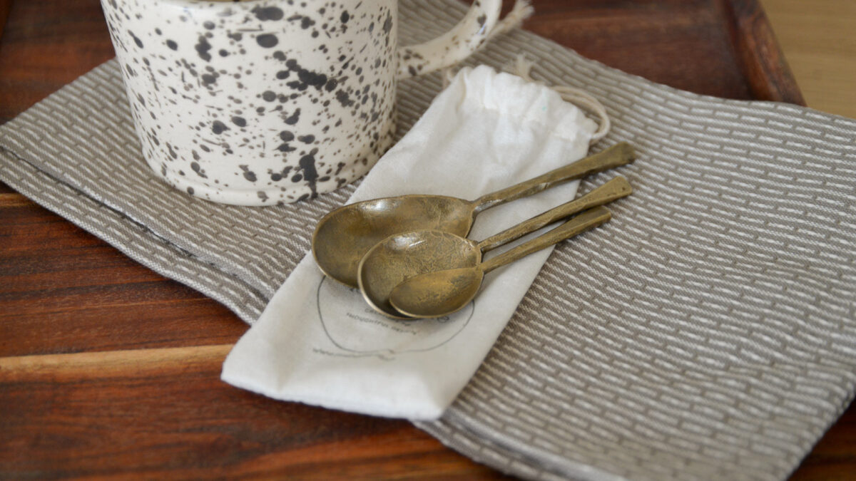 Forged iron spoons sat on the bag that they come packaged in, to show how they will arrive to you.