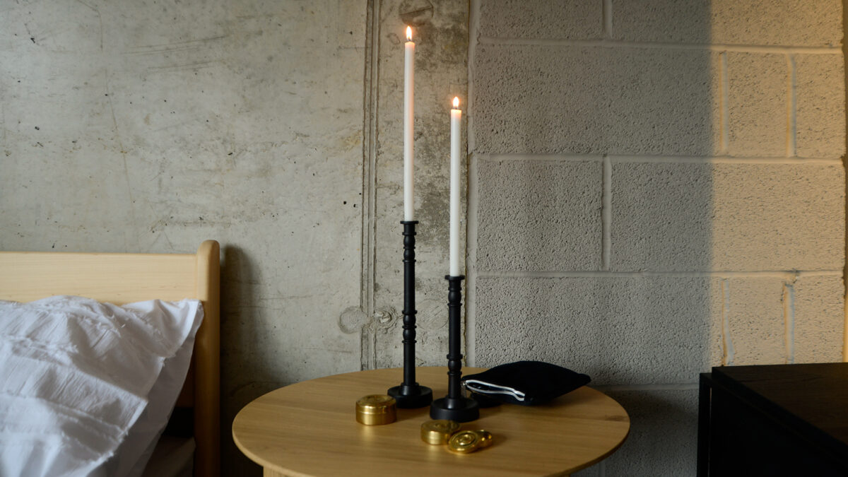 pair of contemporary candlesticks in deep, warm brown-black with brass storage containers on oak table