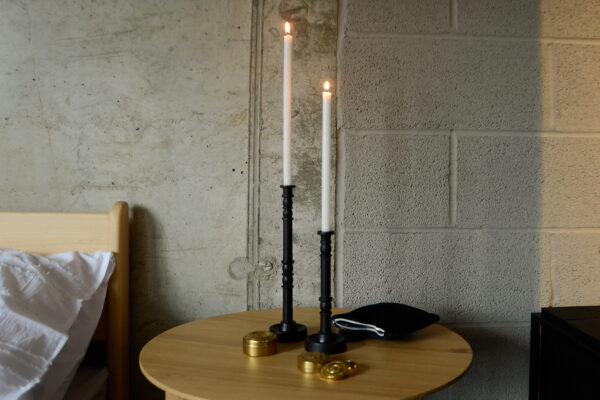 pair of contemporary candlesticks in deep, warm brown-black with brass storage containers on oak table