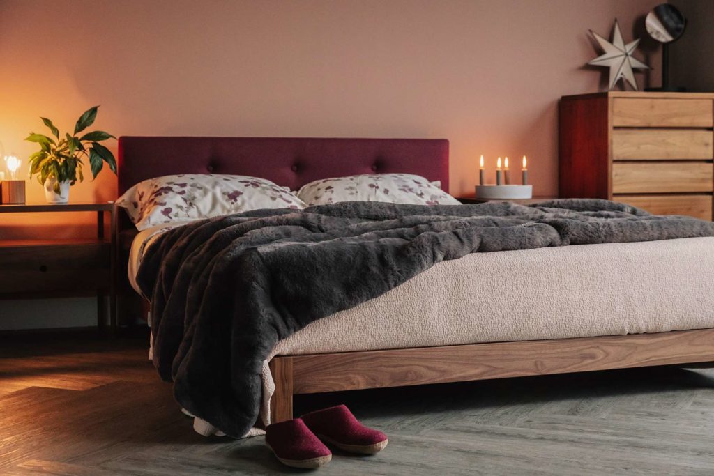 Iona low wooden bed in walnut with upholstered headboard in berry coloured wool fabric