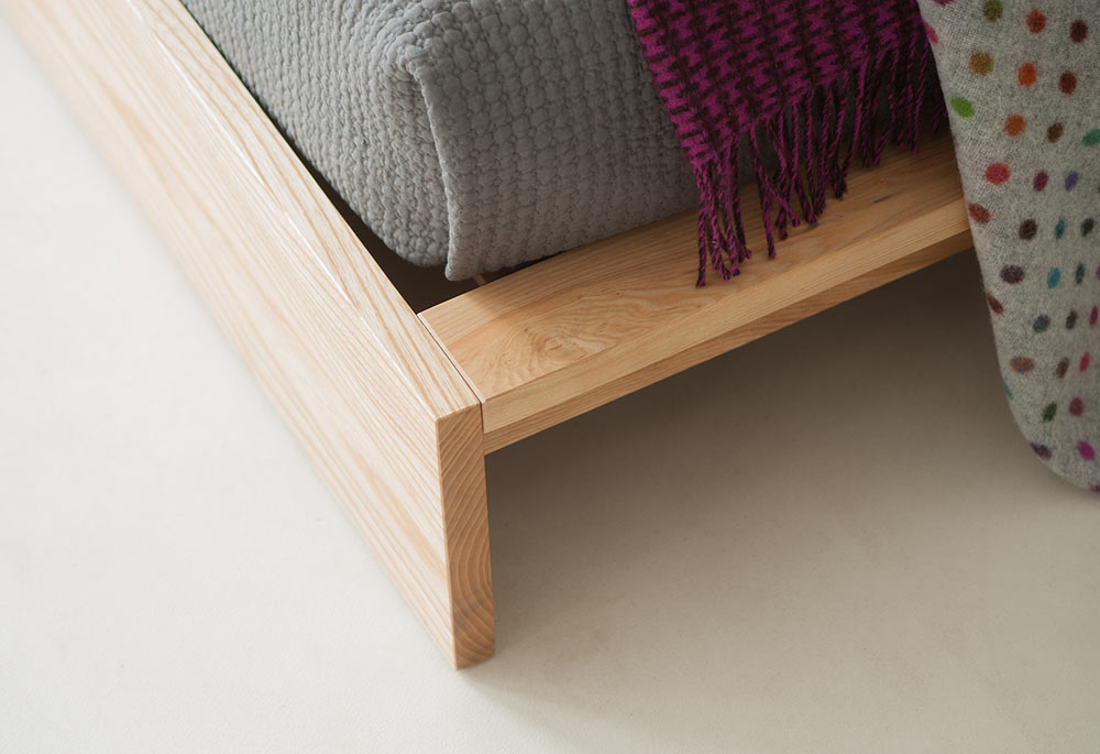 A close up of the foot end of the ultra low wooden Ki bed in Ash