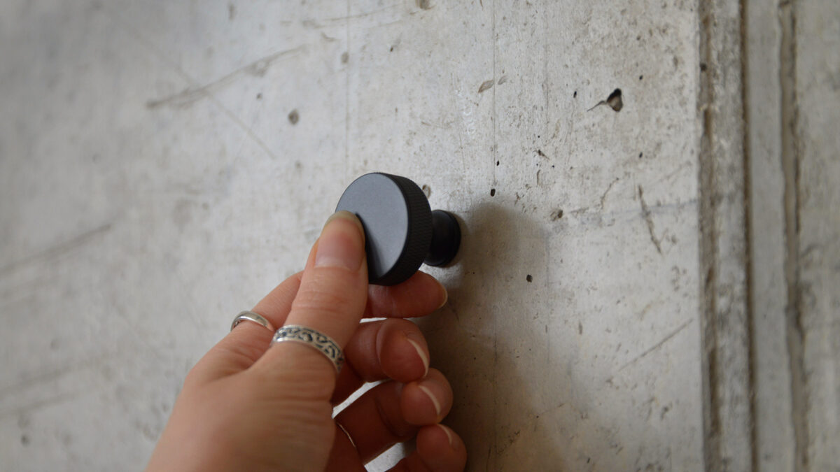 Round Black hook being held onto wall.