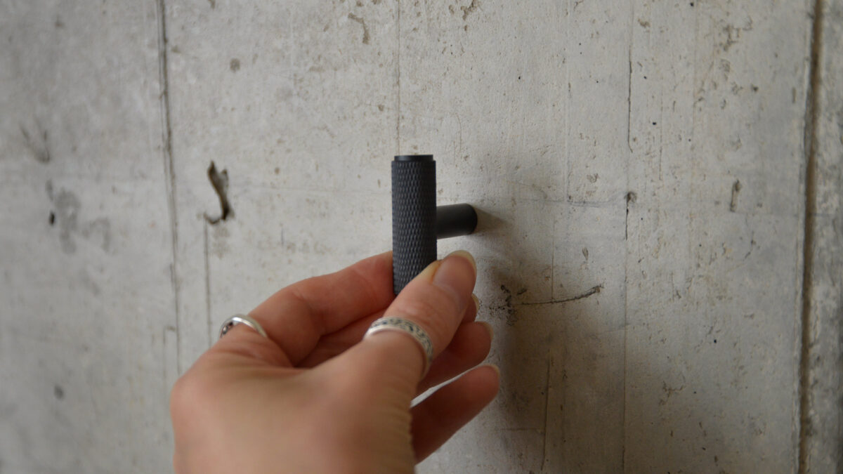 Black T bar hook being held into wall.