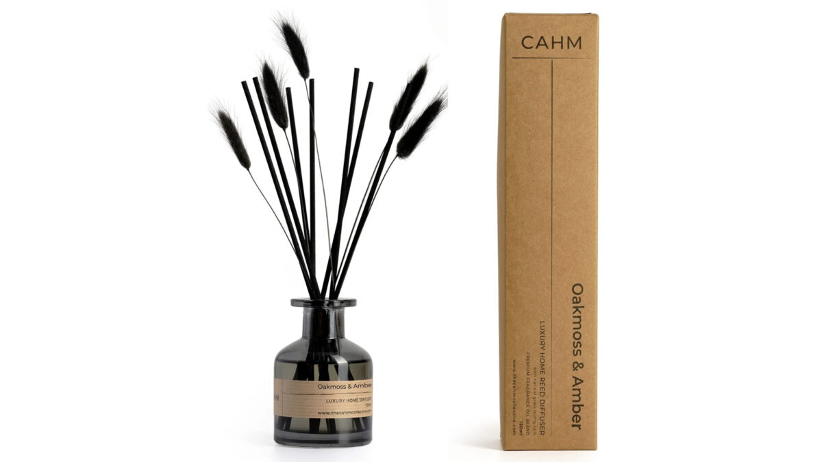 Oakmoss and Amber diffuser in dark glass with black reeds and bunny tails, photographed next to its box.