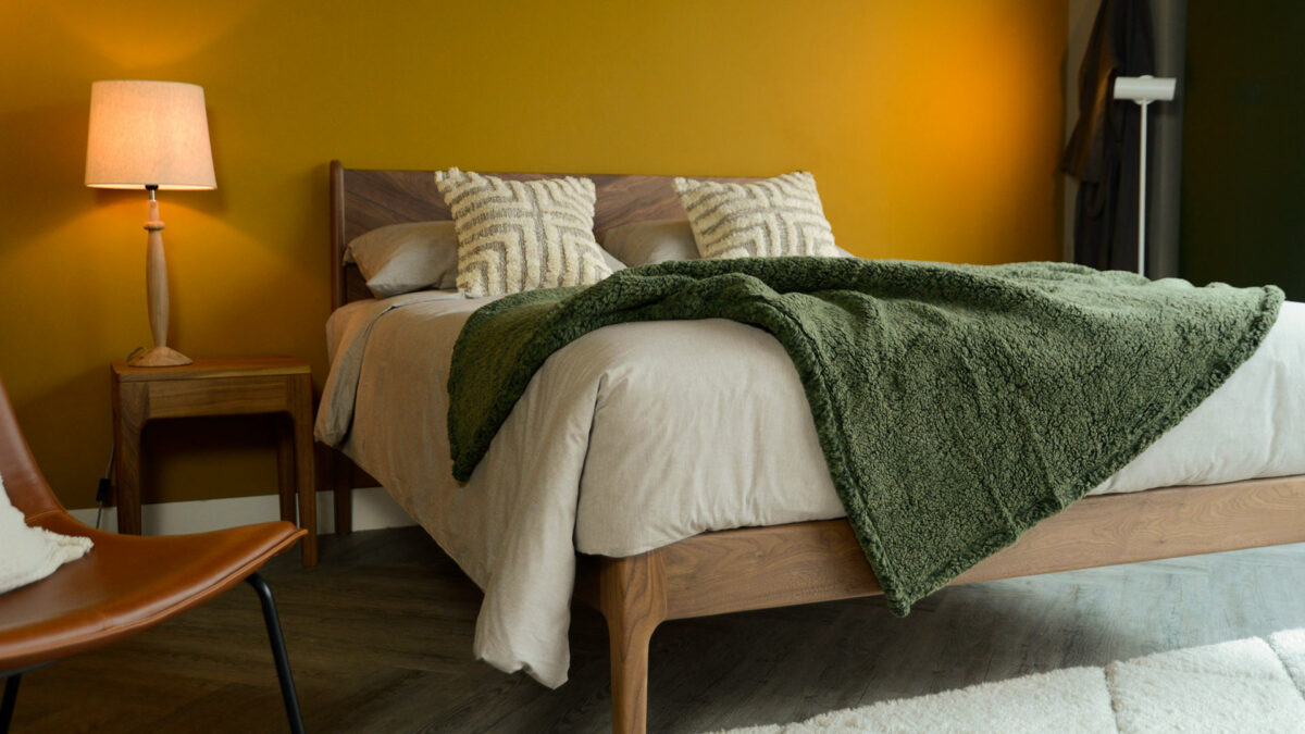 Olive green marl soft and cozy fleece throw shown draped on a Kingsize wooden bed