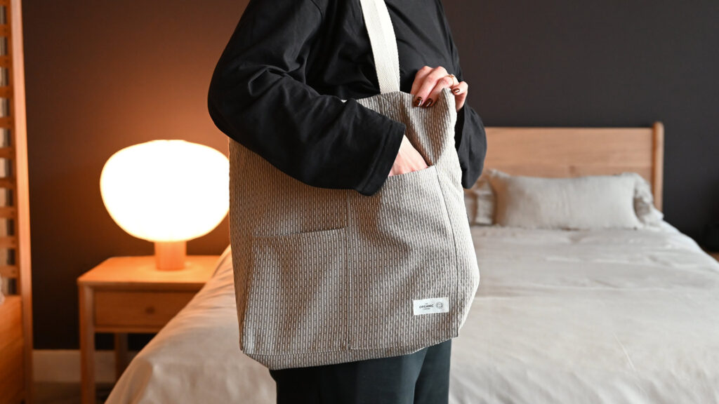 Model wearing clay tote bag with hand in pocket.