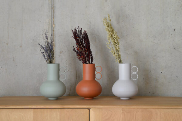 three vases lined up on an oak unit - greige, terracotta and sage.