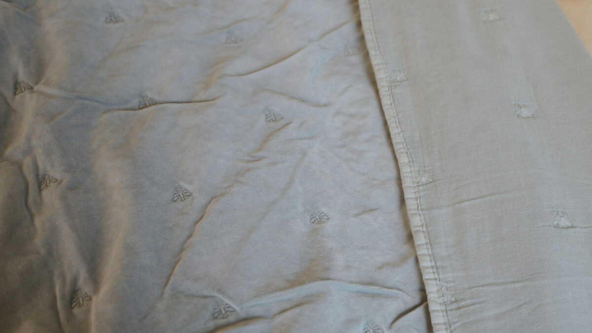 velvet throw with embroidered bee motif in duck egg