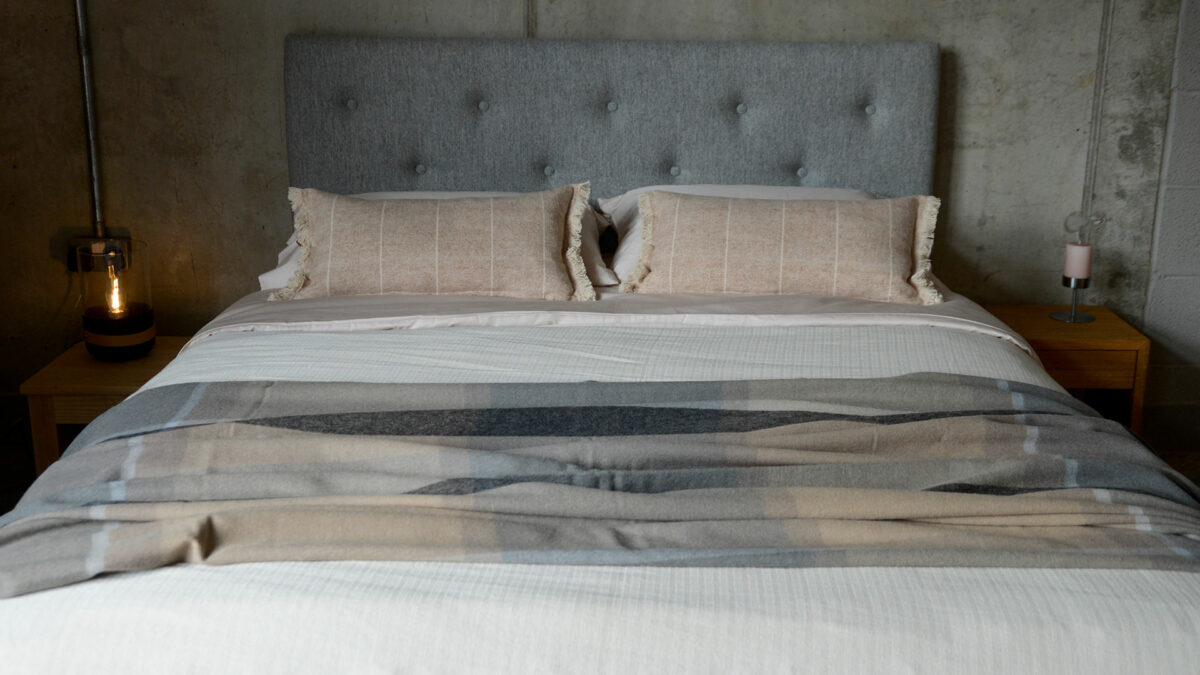 Recycled Alpaca Wool Throw in grey and beige colours shown on a kingsize bed