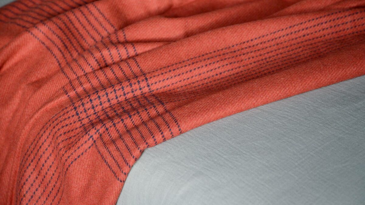 rust red woollen throw with navy threads detail