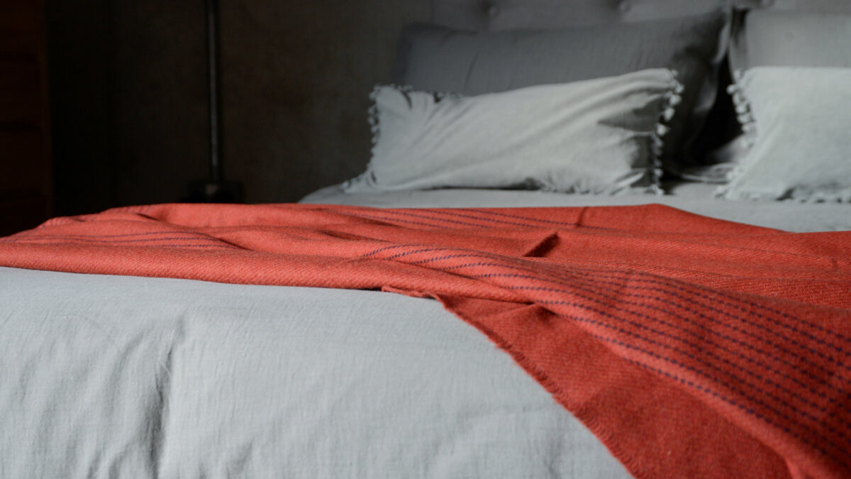 rust red cashmere lambswool throw with navy threads detail