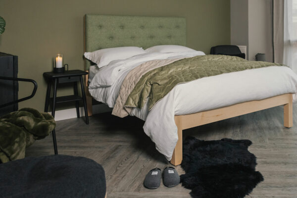 Skye a wooden bed with tall headboard panel upholstered in a green Parquet wool fabric