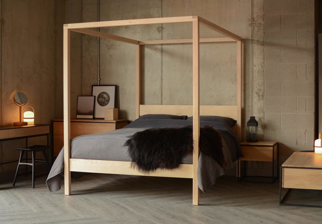 A contemporary handcrafted 4 poster bed this Orchid bed in Maple with dark bedding has a Scandinavian style