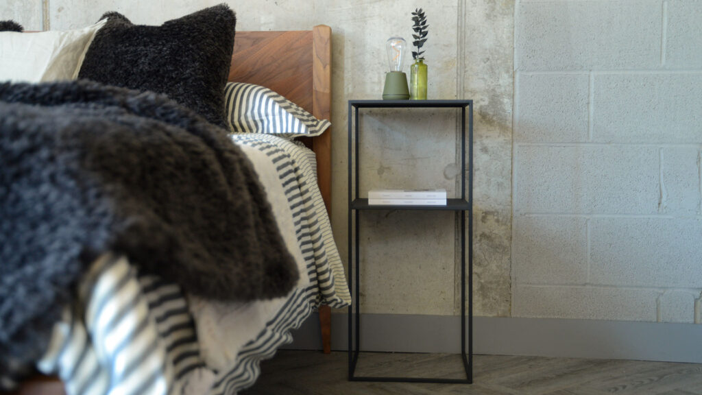 Zoomed out image of tall Fera table showing the full height of the item. Table is stood next to the Dalston bed in solid walnut.