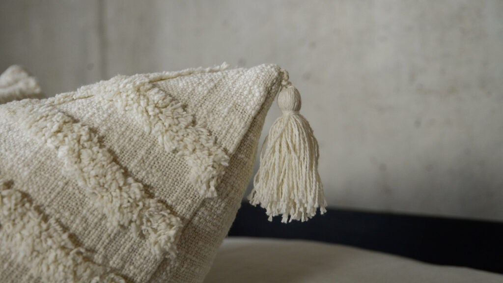 Morocco inspired tufted and tasselled ivory cushions shown close up