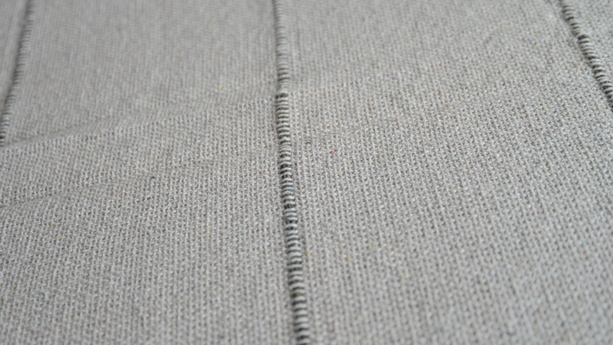 striped and tasselled cotton bedspread in stone and grey shown up close