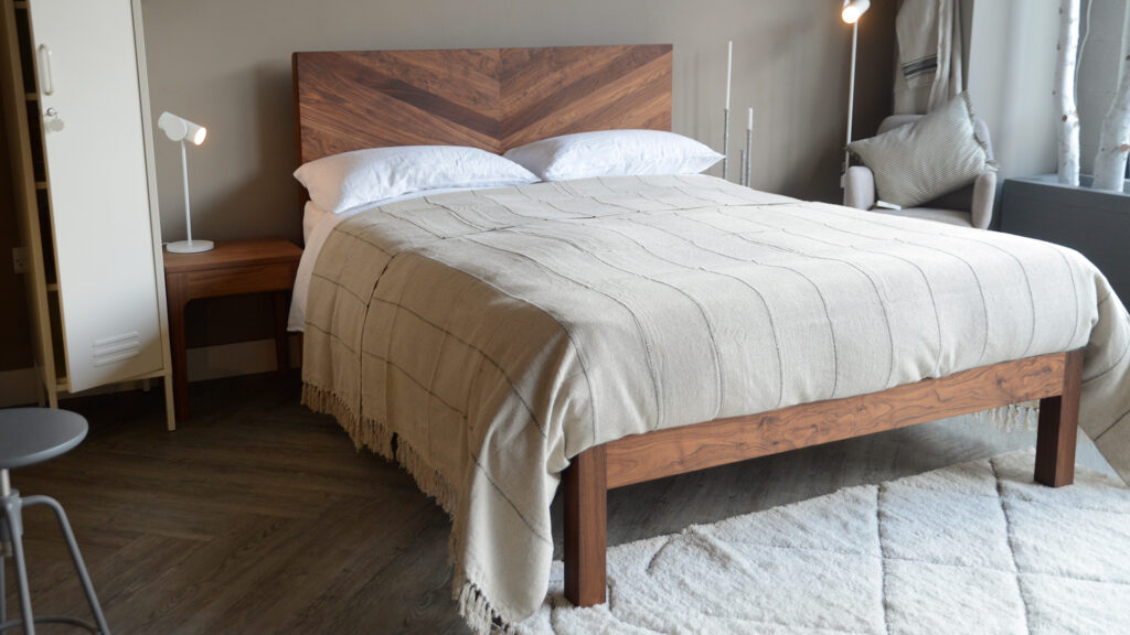 striped and tasselled cotton bedspread in stone and grey shown on a bed